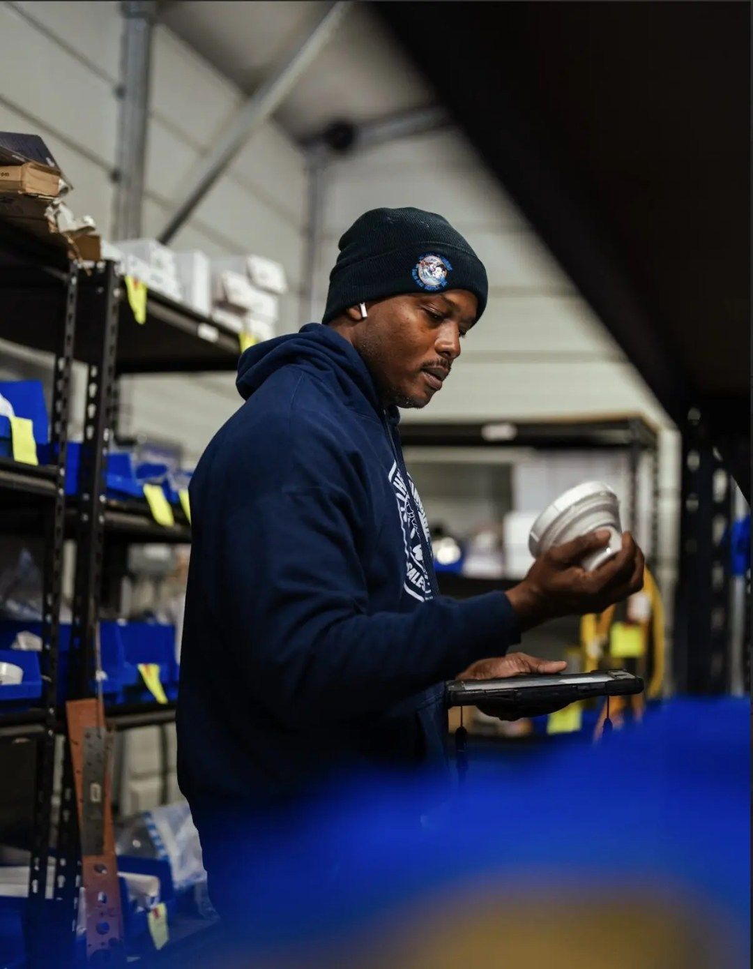 Head's Plumbing tech inspecting a part with a rugged tablet in the parts warehouse.