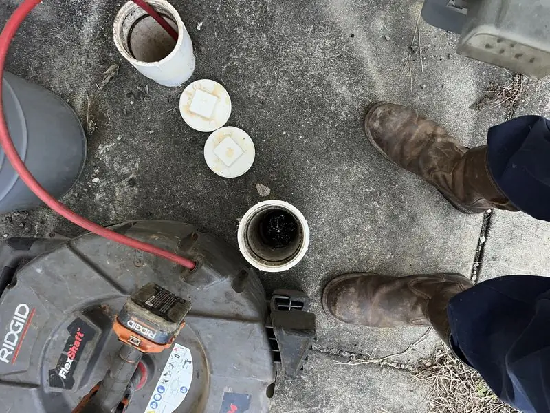 Head's Plumbing tech clearing a drain line through an exterior cleanout.