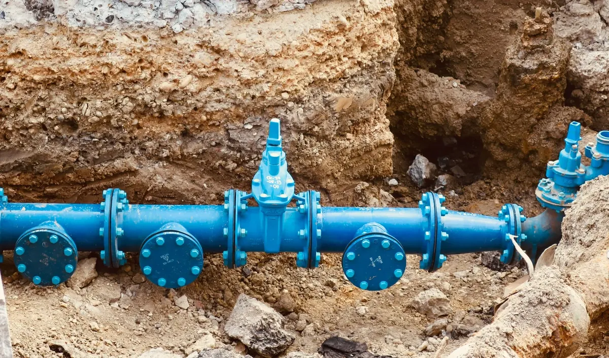 A water main with valves and flanged fittings set in an excavated trench